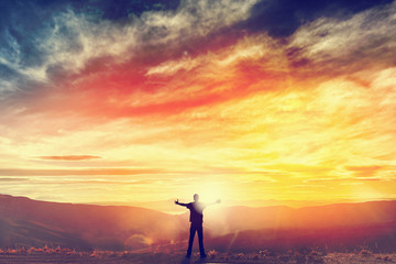 Happy man standing on the peak of the mountain, cliff at sunset. Success, winner, happiness