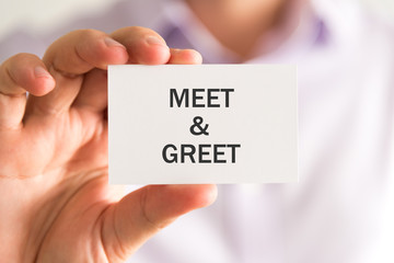 Businessman holding a card with MEET AND GREET message