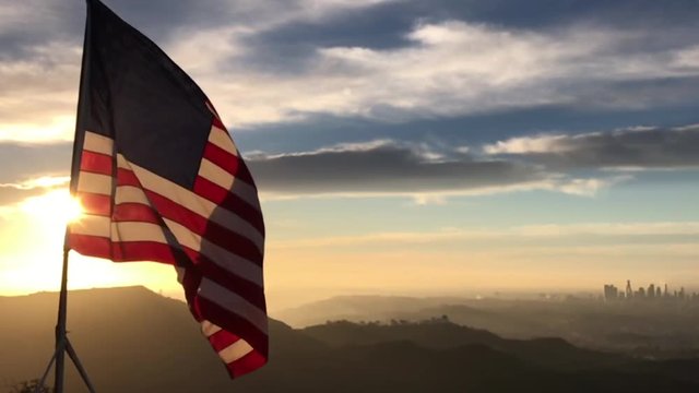 American flag flying in the wind at sunrise over the city of Los Angeles slow motion