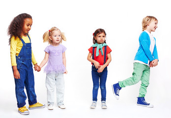 Obraz premium Studio portrait of children against white background: cutout of four kids in bright clothes, two girls holding hands, boy running and confused little girl