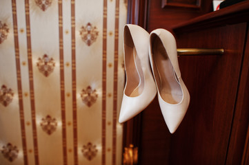 Beige luxury wedding shoes at wooden cabinet on hotel room.