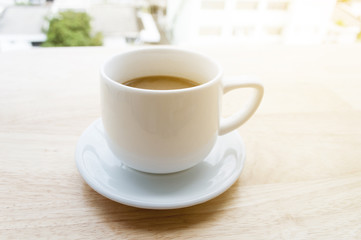 white cup of coffee on wooden table and copy space, soft focus