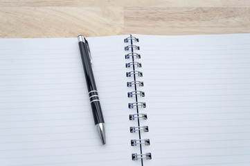 pen on a notebook on wooden table, view from above