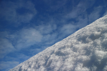 Steep descent mountain slope covered with snow against the blue sky low angle view