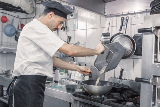 chef transferring pasta pan, commercial kitchen