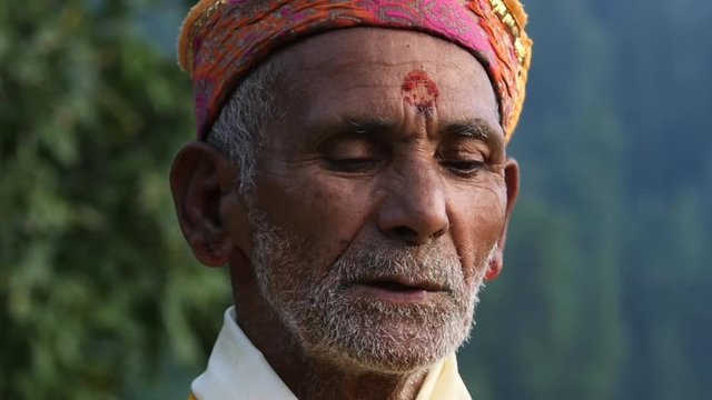 A Hindu old man in yellow national costume offering special spiritual prayer to god in the foothills of the Himalayas, Kullu Valley, India