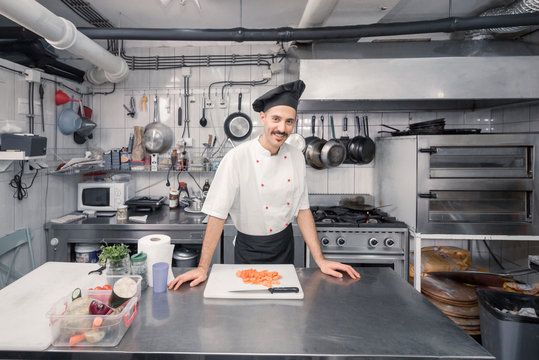 one young chef posing, looking at camera, professional commercial kitchen