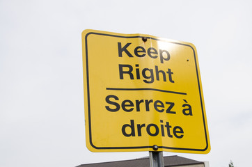 Warning traffic sign for directions in the street. French and English languages to say 