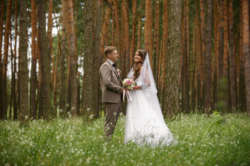 Bride and groom holding hand and looking at each other in forest. Rustic wedding