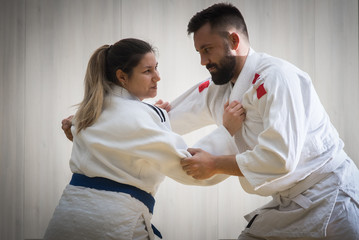 Woman and man judo fighters in sport hall