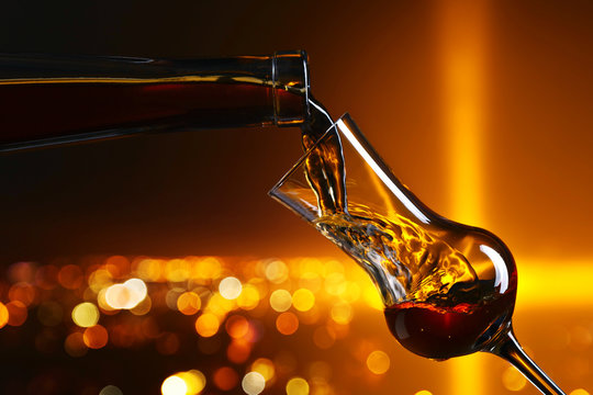 Pouring alcohol into a glass on on the background of night city