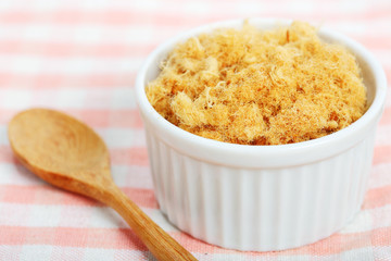 dried pork floss in white cup with wooden spoon