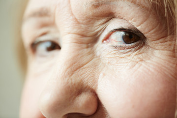 Extreme close-up shot of deep dark brown eyes with wrinkles around them looking at camera