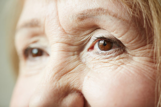 Retired woman with piercing brown eyes looking away thoughtfully, extreme close-up shot