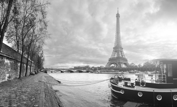 Beautiful panoramic view of the Eiffel Tower and Jena bridge from the river Seine embankment. Dramatic cloudscape. Traditional citycape in backlit morning sunbeam. BW photography. Paris, France.