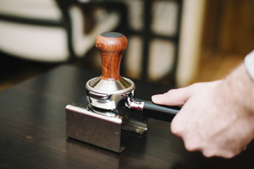man using a tamper to press freshly ground coffee into a tablet