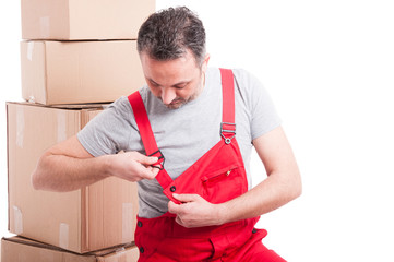 Mover guy surrounded by cardboard boxes fixing his overall