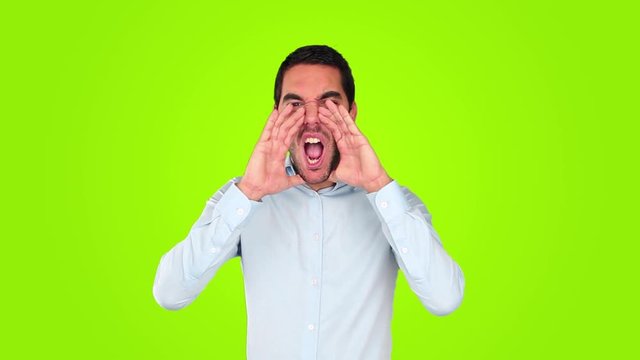 Young man shouting against green background