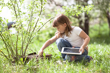Naklejka na ściany i meble Kids girl playing with tablet on stump, childhood