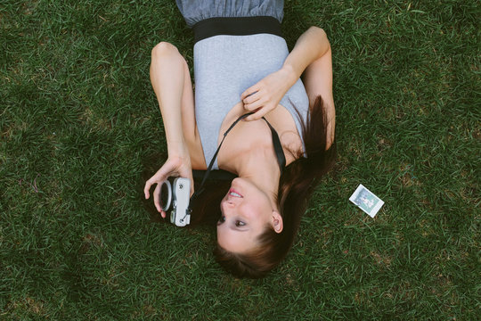 Young Girl Lying on the Grass Taking Pictures With a Vintage Camera