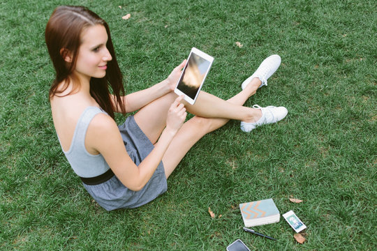 Young Beautiful Girl Usign an Ipad in the Park