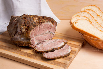 Baked pork with herbs and spice on wooden board and and slices white wheat bread.