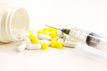 Medical syringe and pills on white background.