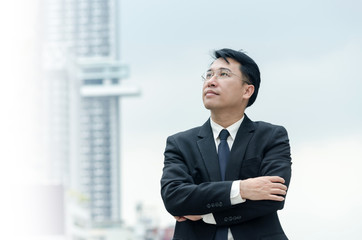 Portrait of asian businessman with arms crossed standing.