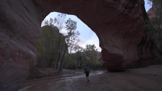 Backpacker walking under Coyote Natural Bridge Glen Canyon National Recreation Area