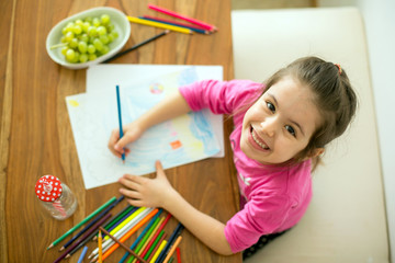 Cute little girl, drawing picture with pencils at home