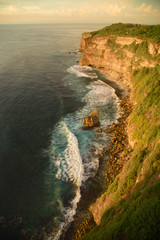 Fototapeta na wymiar Ocean waves breaking on the rocks at the foot of a mountain cliff.