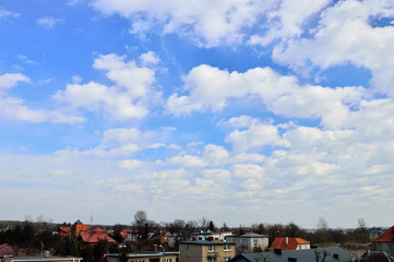 Chmury na niebieskim niebie nad dachami domów.