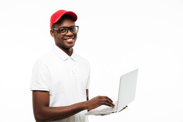 Happy young african man wearing cap using laptop computer