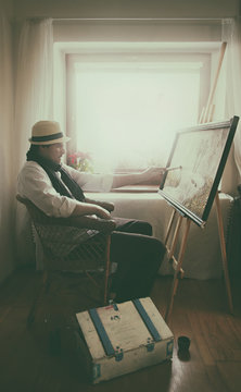 Artist Painting on Canvas in His Studion with Light Coming From Window