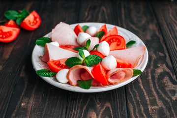 salad with tomatoes, meats, herbs and mozzarella cheese