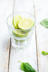 ingredients for a mojito in a glass on a white wooden background.