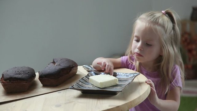 Pretty little girl eating butter with her finger. Homemade bread. Enjoying taste