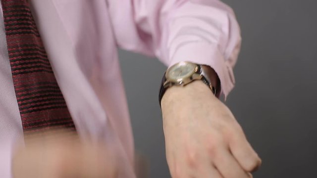 Male tapping his wrist-watch and checking time, broken mechanical watch