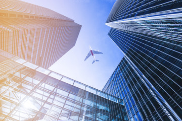 Fototapeta na wymiar Airplane flying over business skyscrapers.