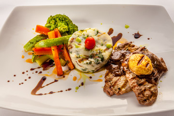Beef steak with mashed potatoes and vegetables on a white plate