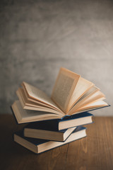 stack of books on a wooden table and on gray concrete wall background