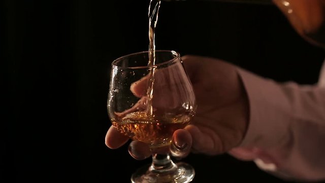 Connoisseur of expensive alcoholic drinks pouring cognac into glass and tasting