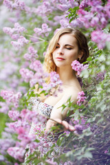 Obraz na płótnie Canvas young woman smelling a lilac