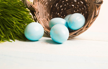 Blue Easter eggs in basket on wooden background