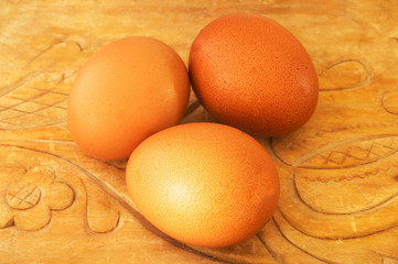 Three brown eggs on a carved wooden base