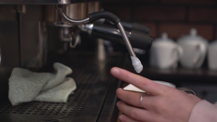 Barista preparing cappuccino on coffee machine.