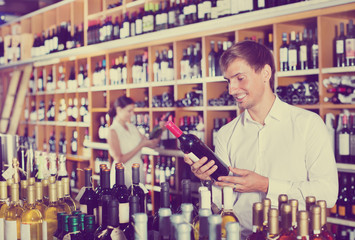 Cheerful man buying bottle of wine