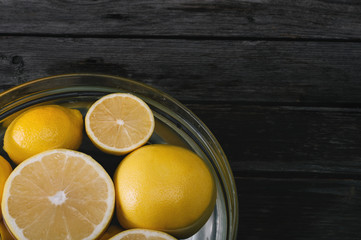 A bunch of cut and whole lemon and grapefruit in a bowl full of water. Selective focus and small depth of field.