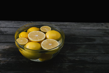 A bunch of cut and whole lemon and grapefruit in a bowl full of water. Selective focus and small depth of field.