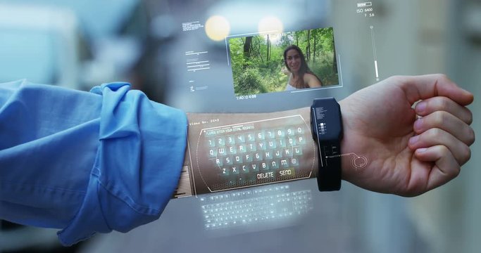 A man answers the wife who smiles and waves from the phone that appears in hologram clock futuristic and technological. Concept: network, communication,family, technology, augmented reality and future